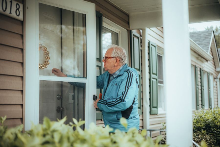 persona mayor cerrando la puerta de una casa